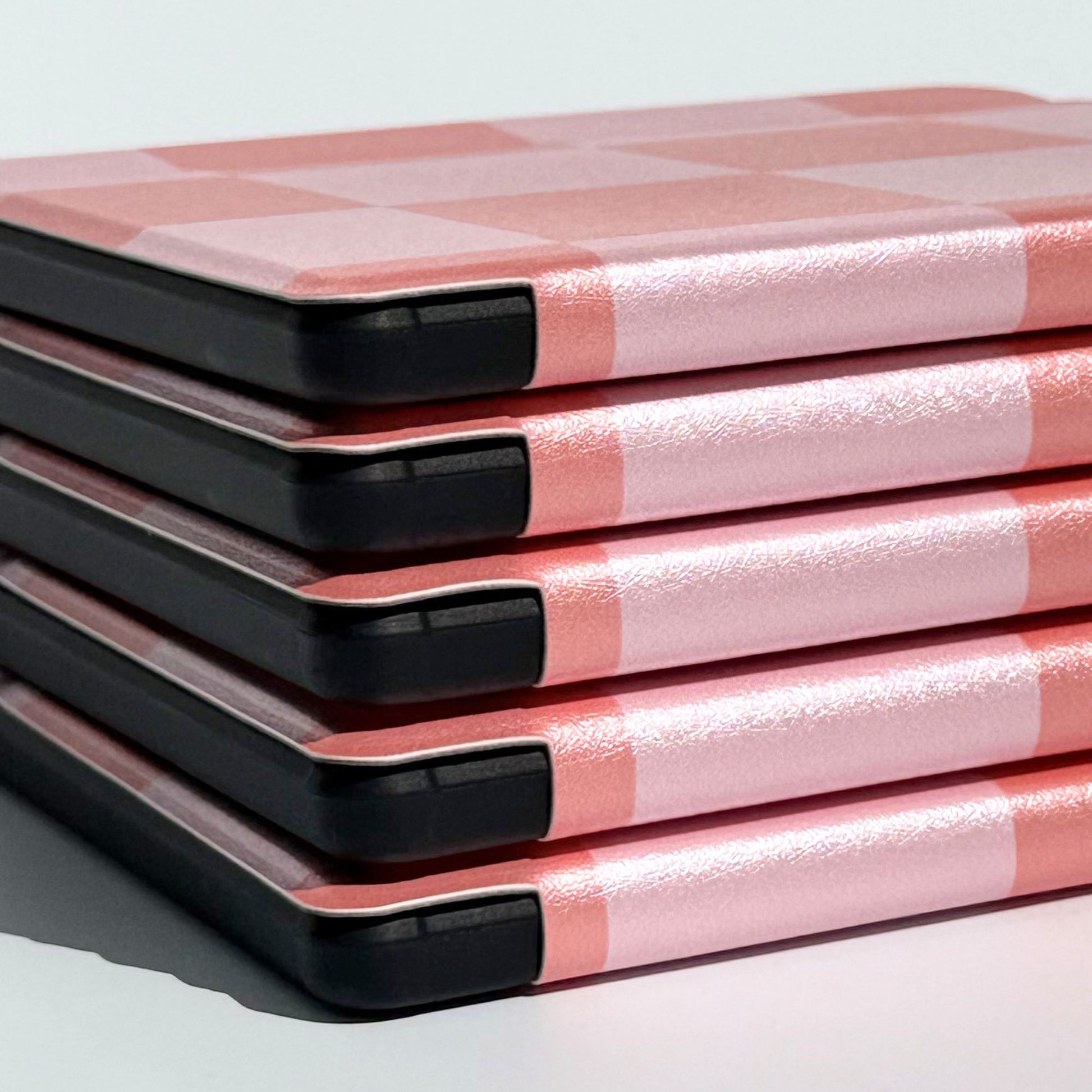 Side profile of Fairy Tales Kobo Libra cases stacked, coral and pink check spine detail with black shockproof bumper corners