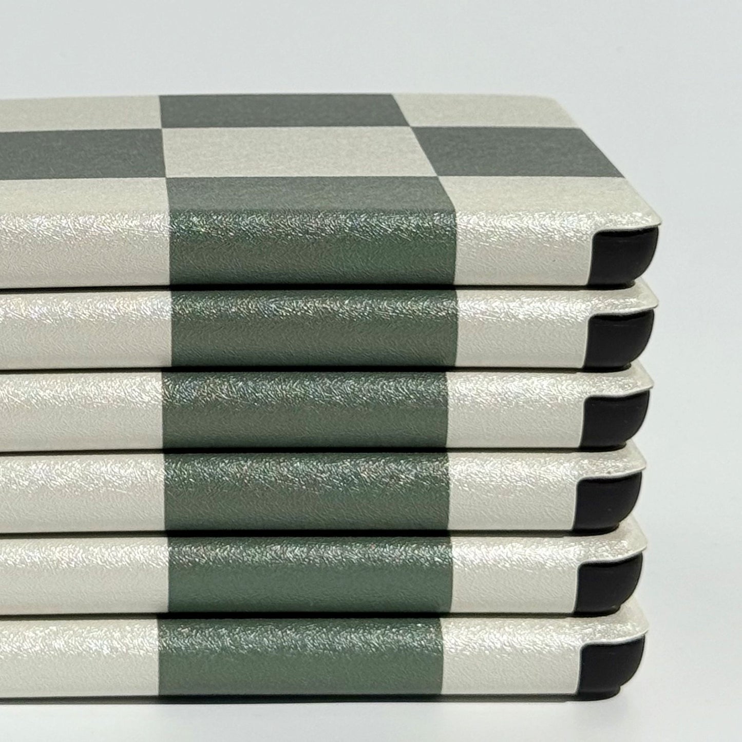 Side stack of Forest Lore Kindle cases highlighting slim profile and green and cream edges