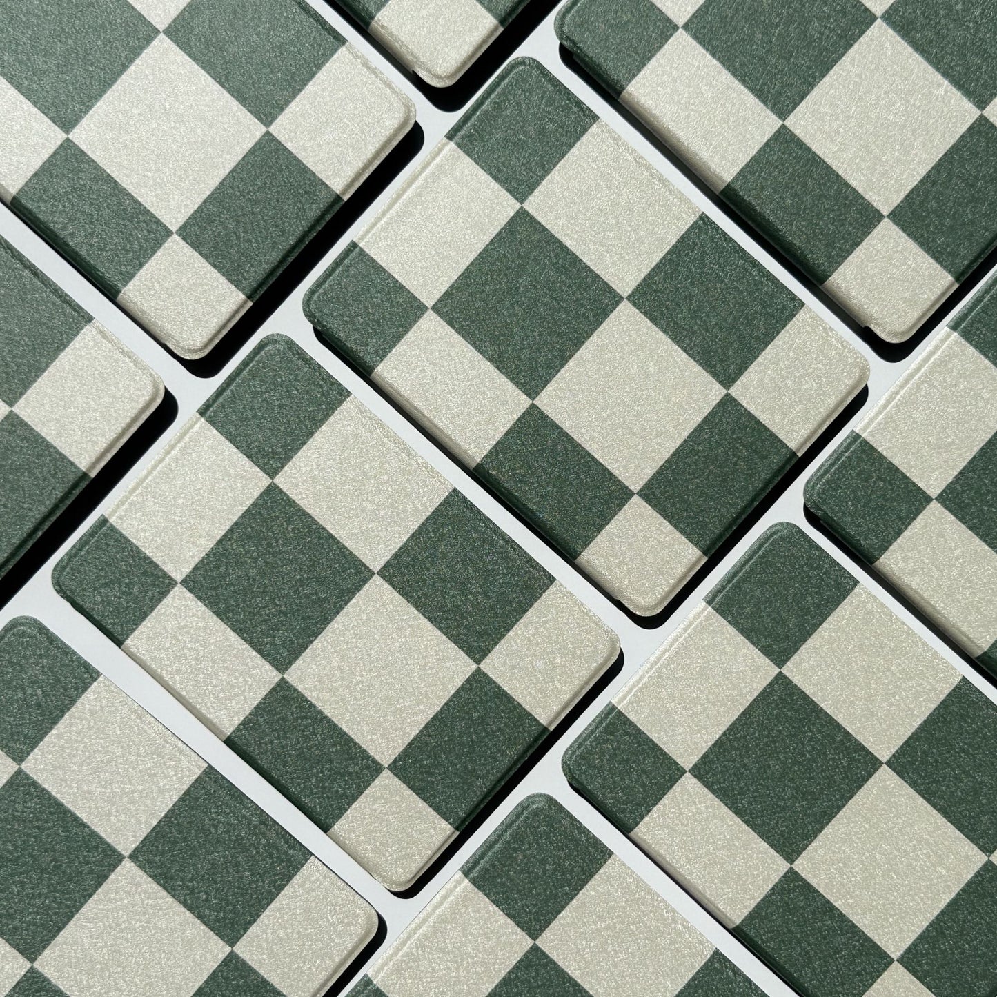 Flatlay of Forest Lore Kindle cases in a diagonal grid showing green and cream checkerboard pattern