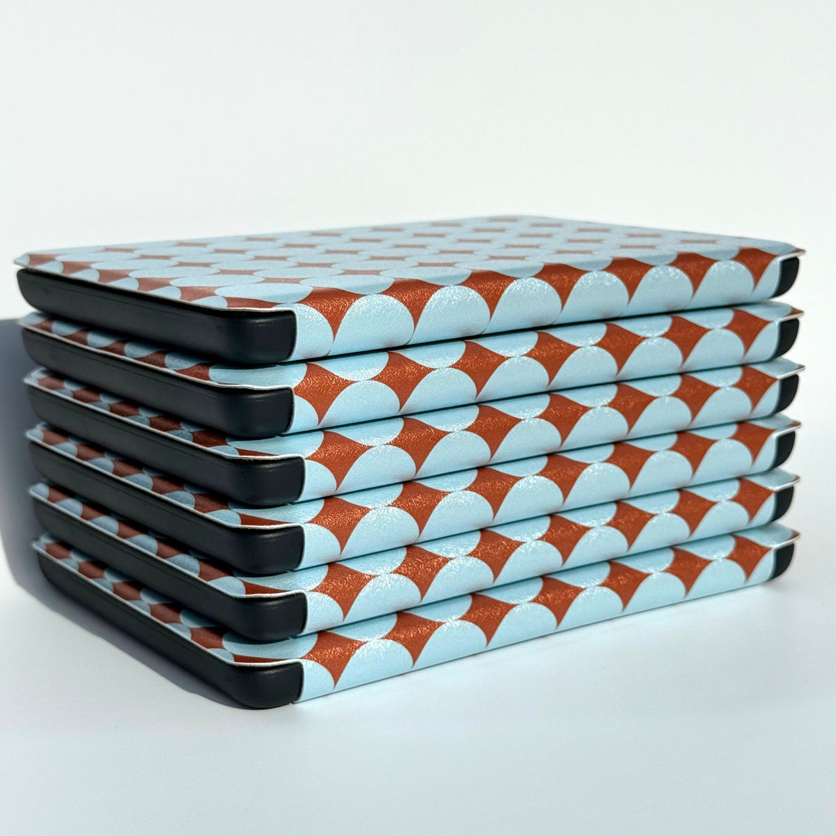 Six retro blue and copper polka dot Kindle cases stacked on a white background