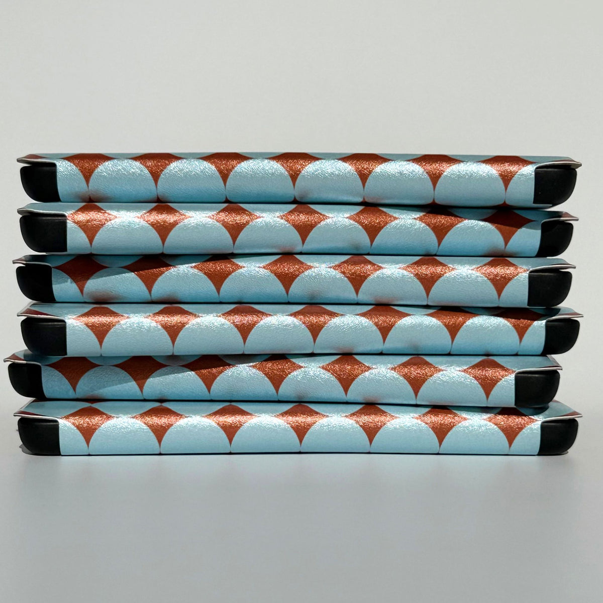 Blue polka dot Kindle cases from Case Society Australia, stacked six high with copper diamonds