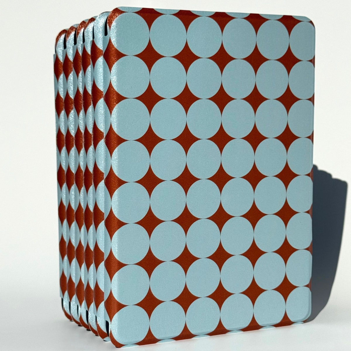 Blue polka dot Kindle cases fanned upright, copper shimmer glinting between soft blue dots