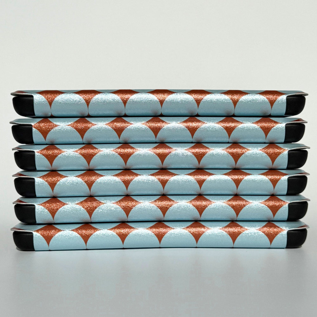 Stack of blue dot Kindle cases showing black shockproof corners and copper spine pattern