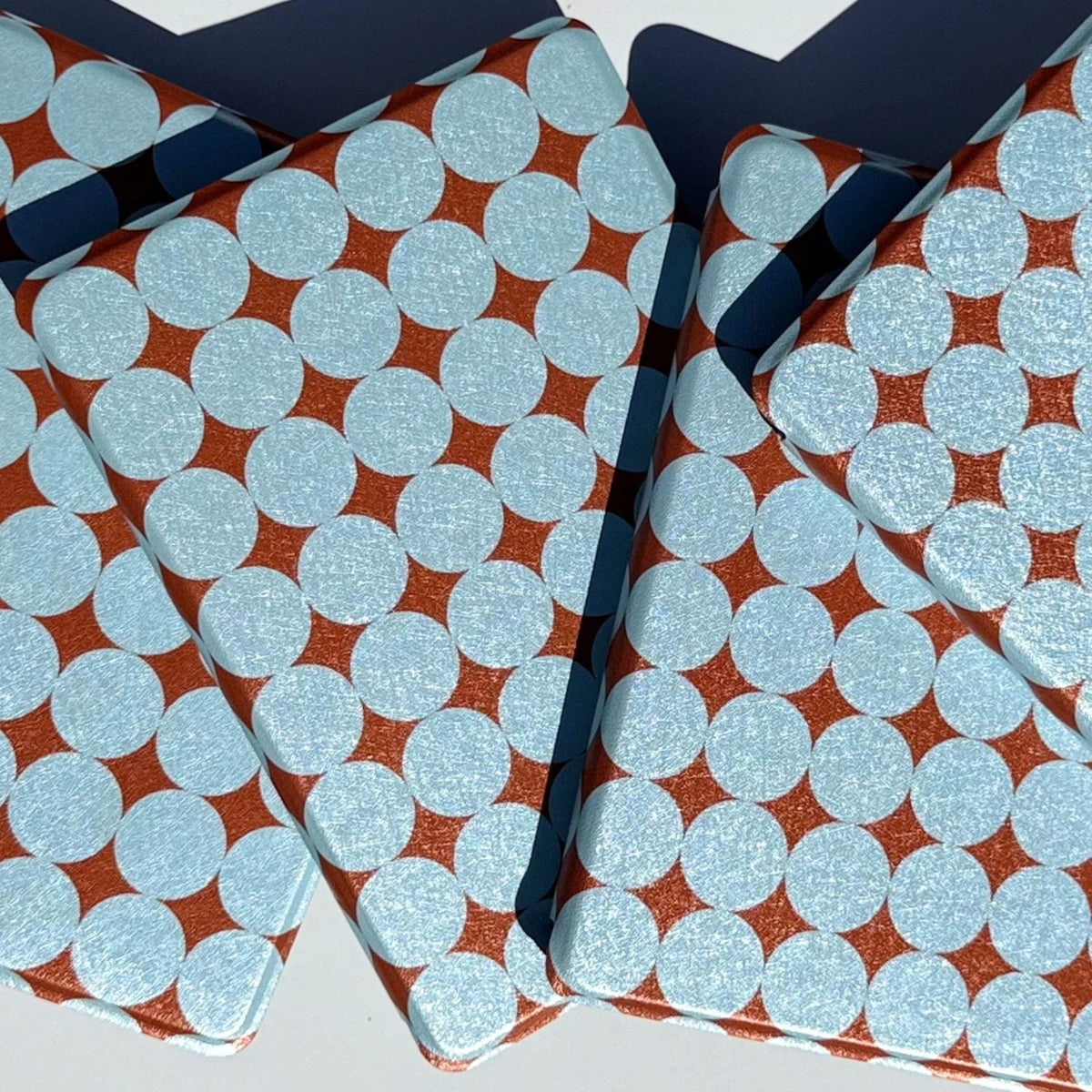 Overlapping retro dot Kindle covers in sunlight, textured powder blue circles on metallic copper
