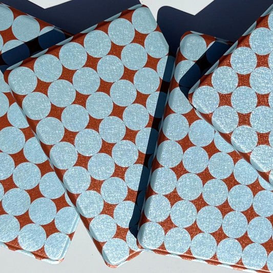 Overlapping retro dot Kindle covers in sunlight, textured powder blue circles on metallic copper