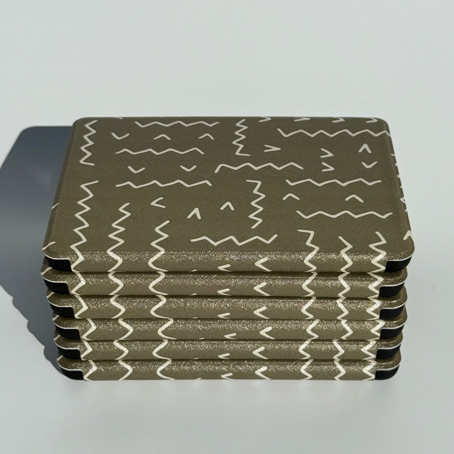 Stack of Off Script olive green zigzag Kindle cases, spine view