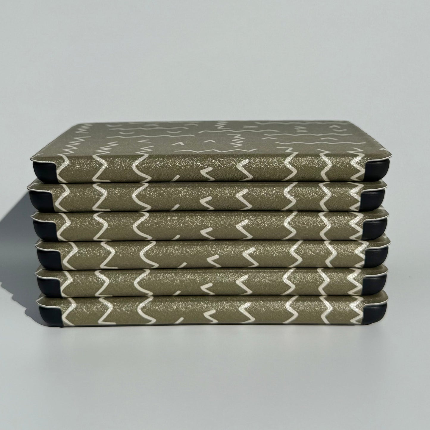 Side stack of Off Script olive green zigzag Kindle cases showing the slim profile
