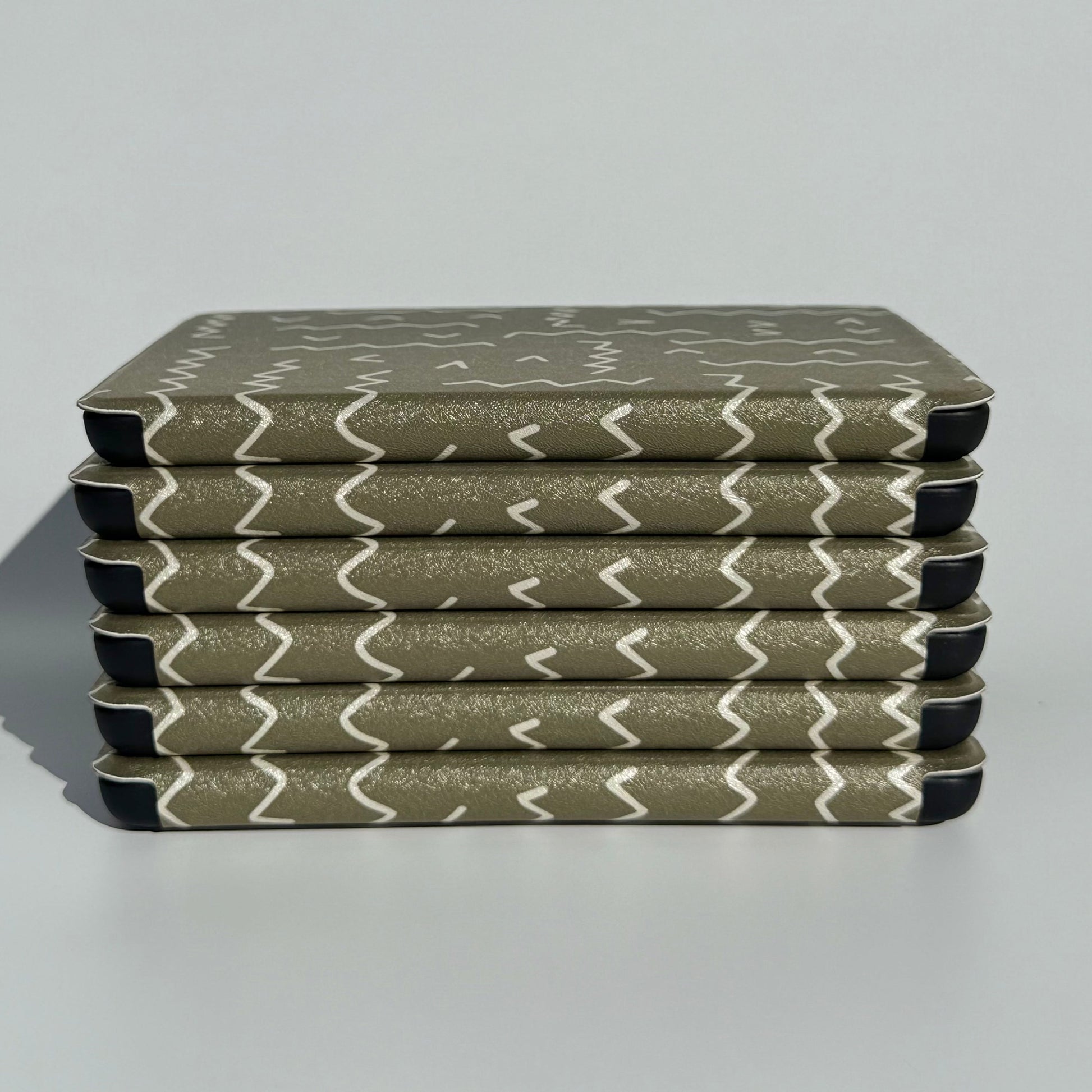 Side stack of Off Script olive green zigzag Kindle cases showing the slim profile