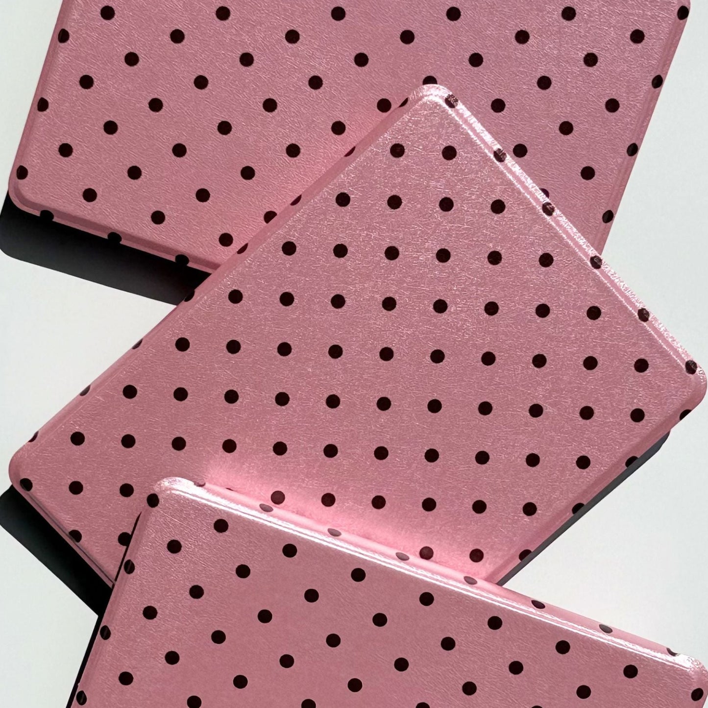 Three Pink Reverie Kindle cases fanned out, pink polka dot Kindle Paperwhite covers