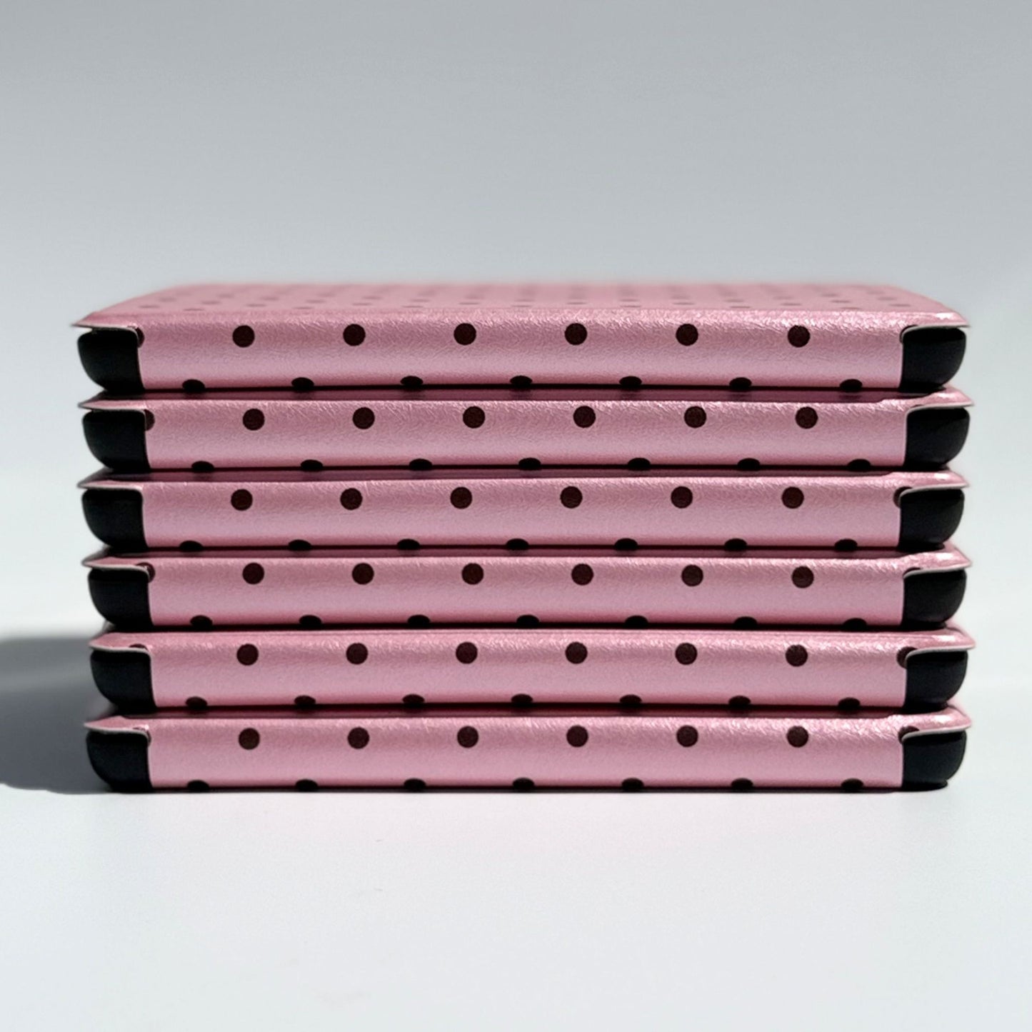 Slim stack of Pink Reverie pink polka dot Kindle cases, front edge view