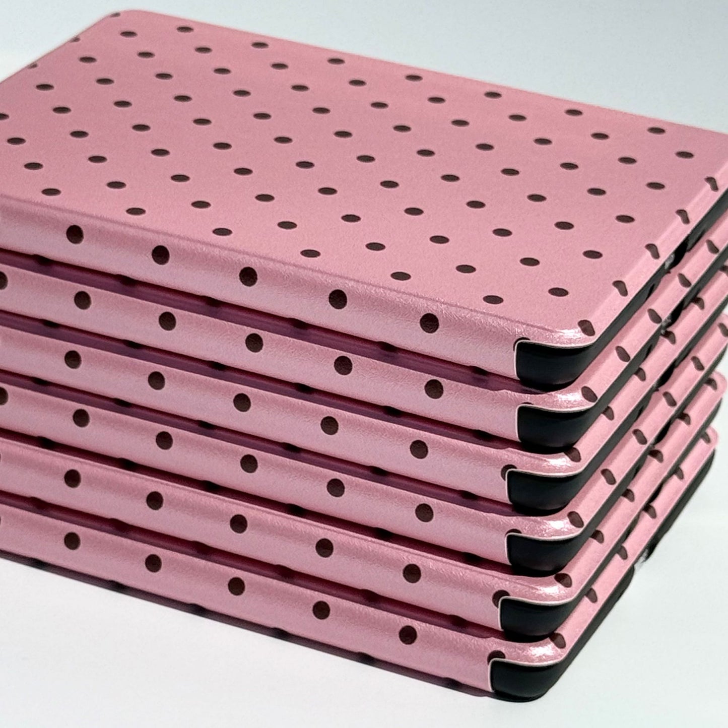 Angled stack of Pink Reverie Kindle cases, pink polka dot folio covers