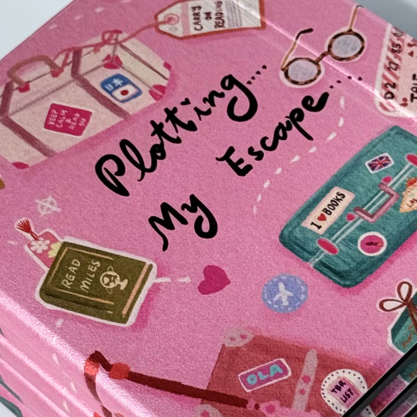 Three Plotting My Escape Kobo Libra cases overlapping showing cute pink ereader cover with books and suitcases