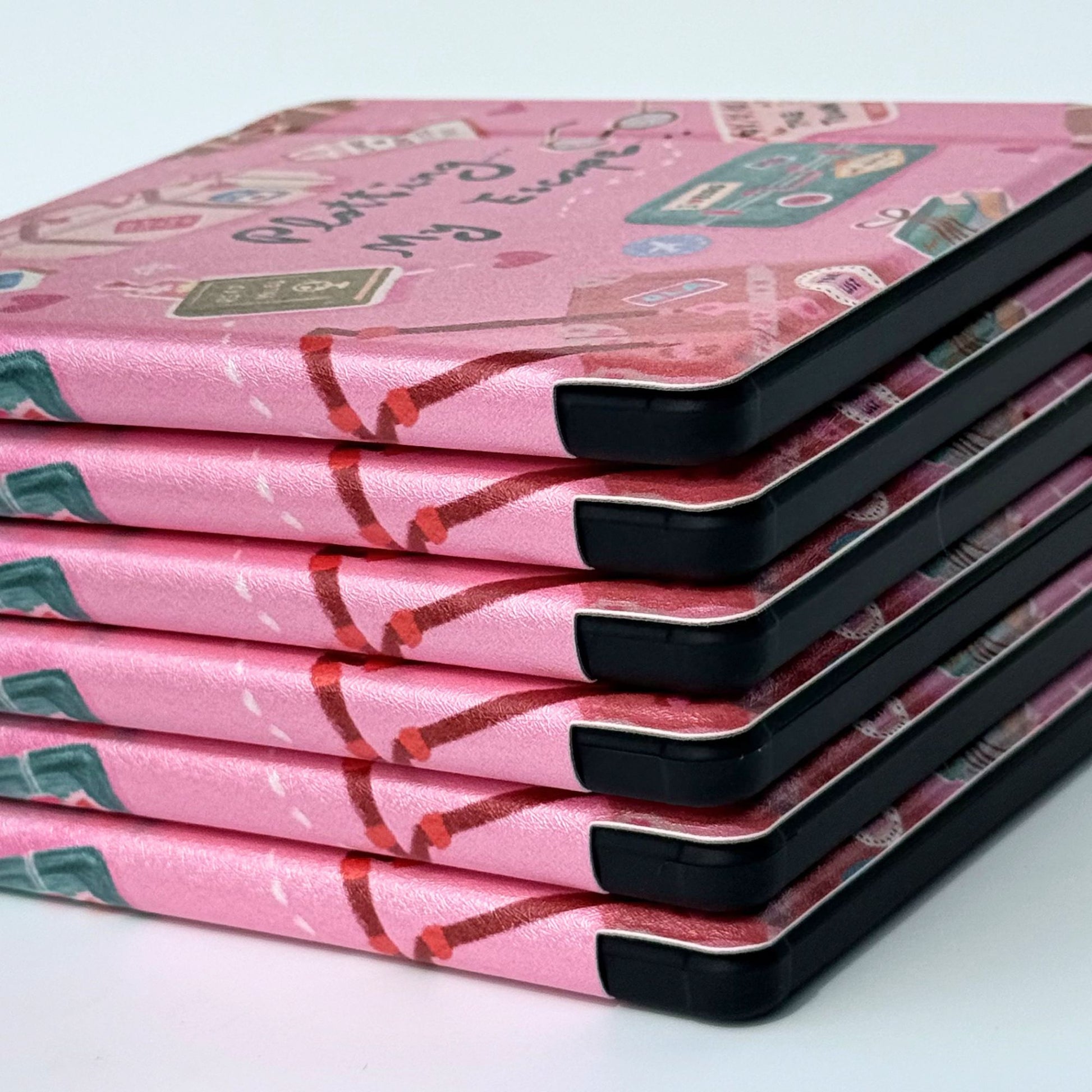 Close-up of Plotting My Escape Kobo Libra case cover featuring vintage suitcases, books and travel tags on pink background