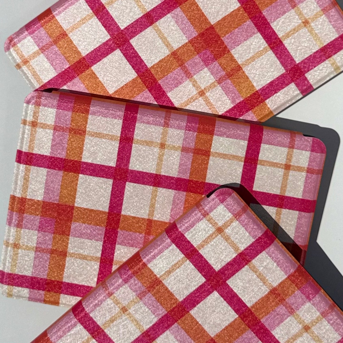 Close-up of Roseline Kindle cases showing the pink and orange plaid pattern with shimmer finish