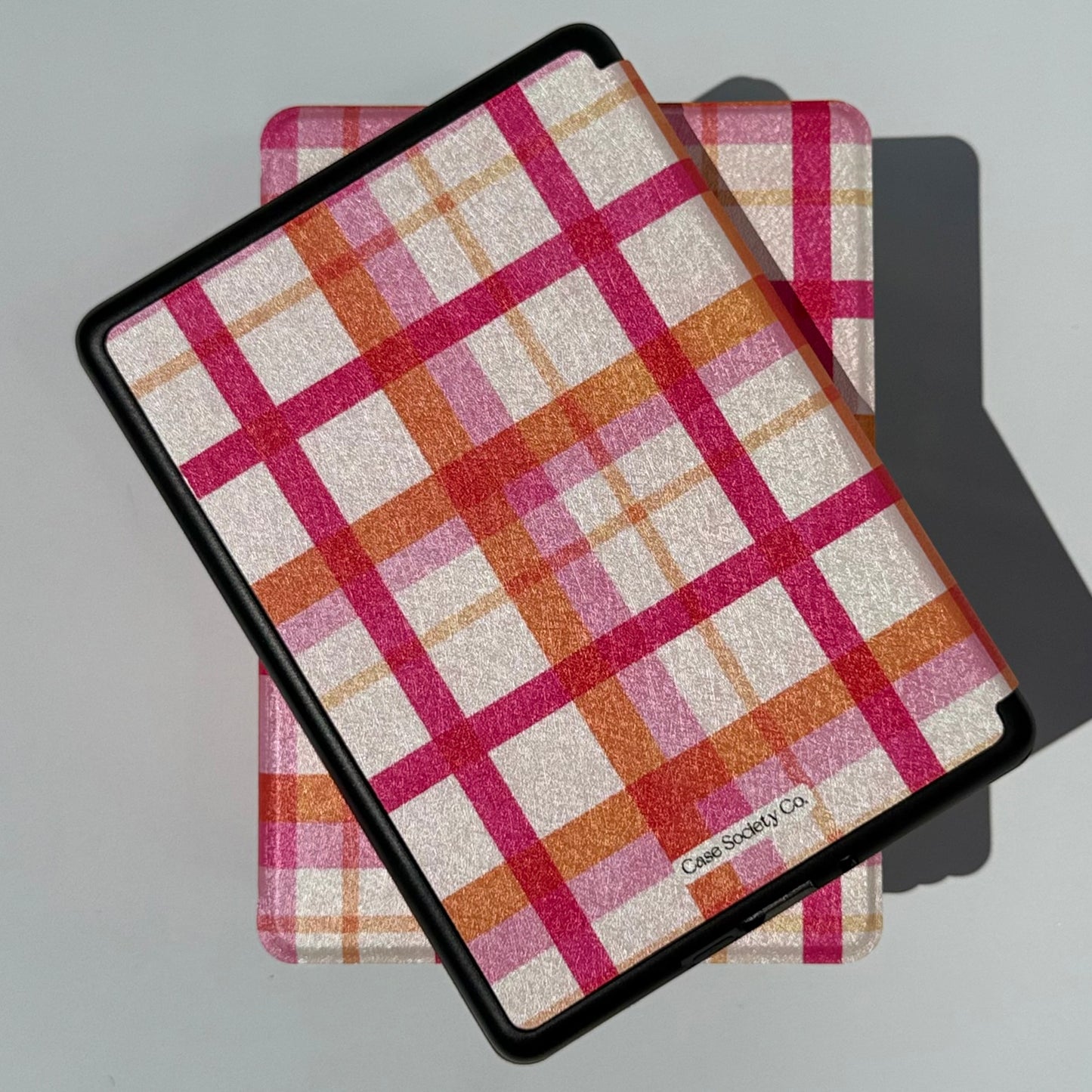 Two Roseline pink and orange plaid Kindle cases stacked in sunlight, Case Society Australia