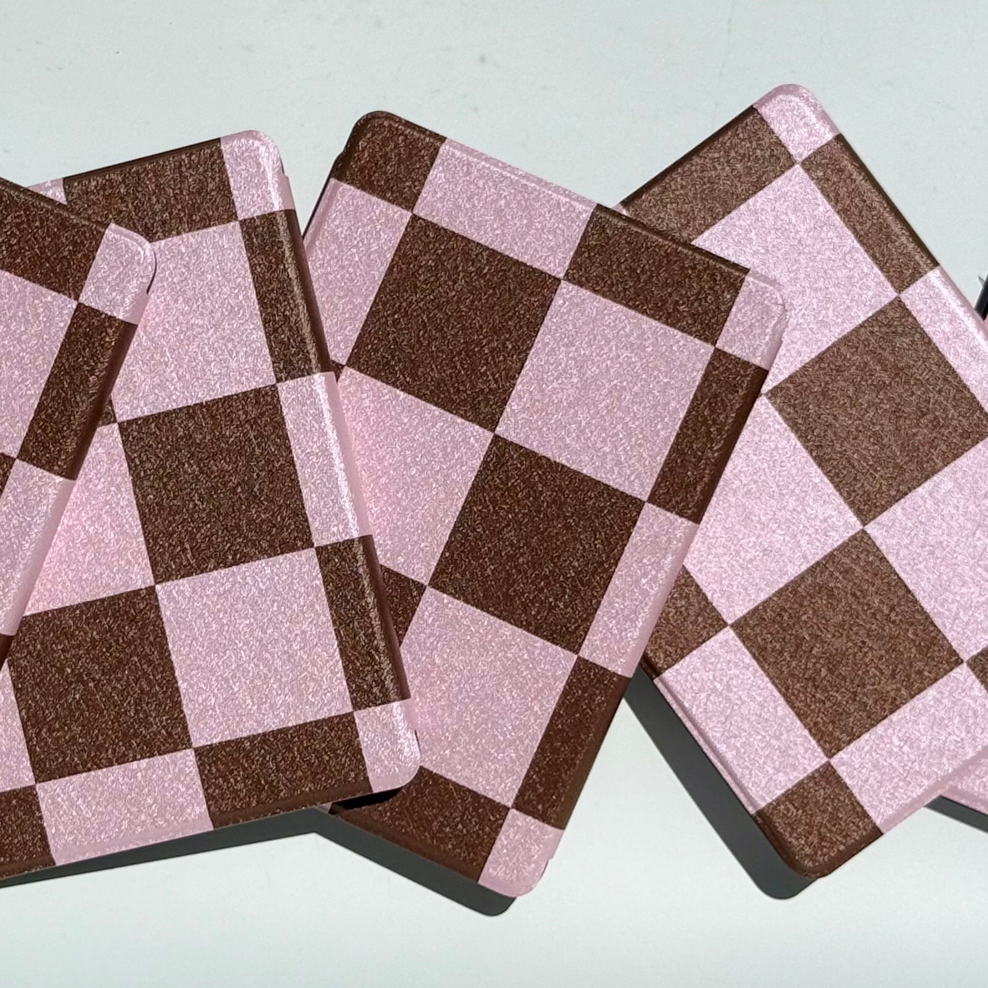 Two She's Checked In pink and brown checkered Kindle cases propped on edge — aesthetic bookish case