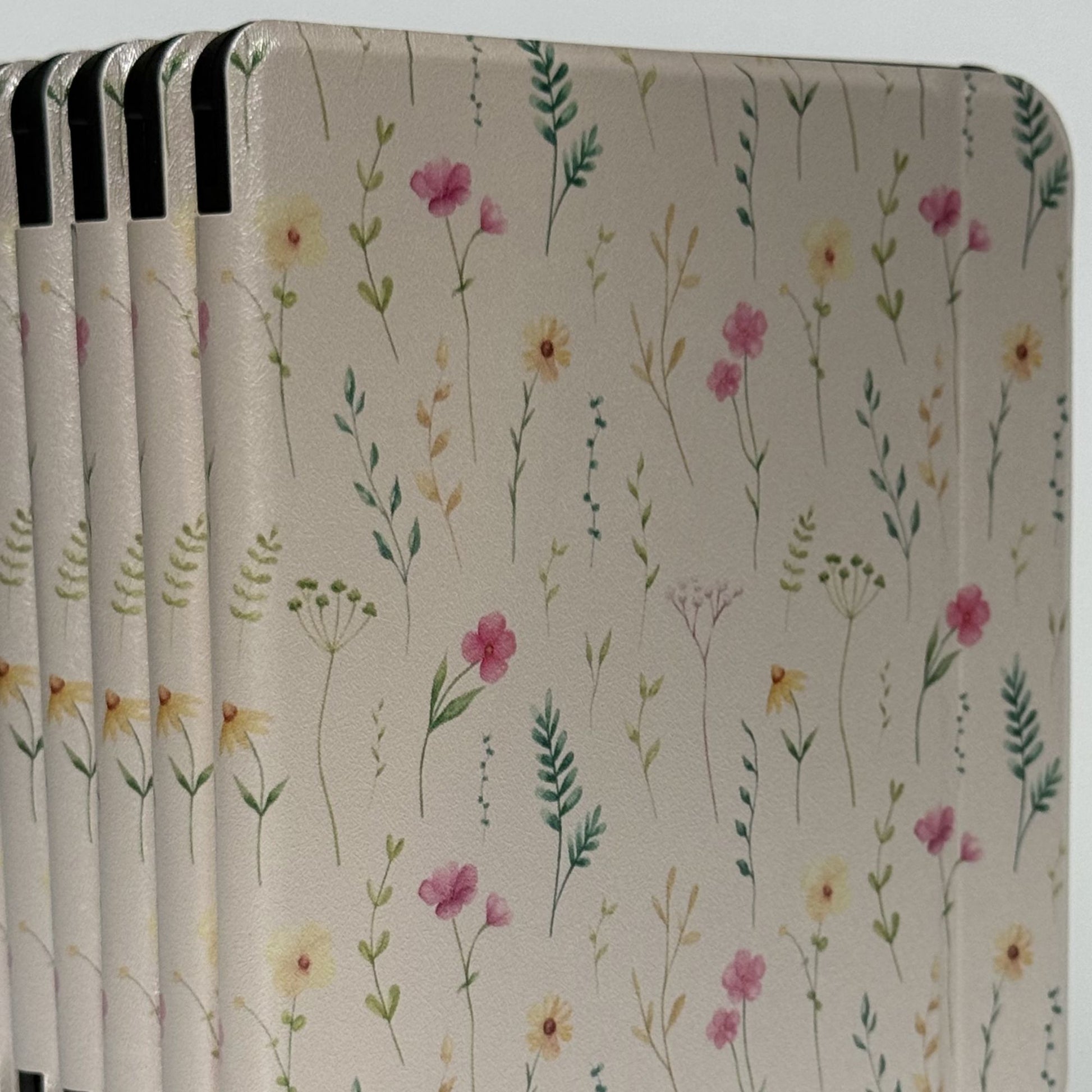 Pair of Spring Court Kobo Libra cases stacked, cream fairycore wildflower print with pink, yellow and green botanicals