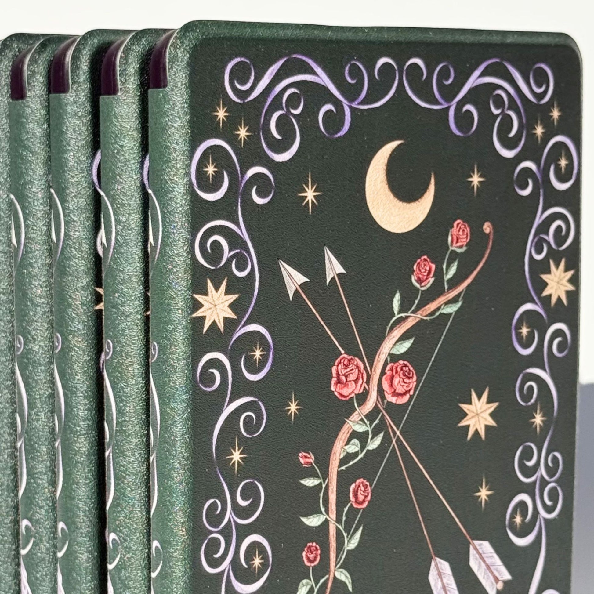 Close up of The Huntress Kindle case, gold crescent moon, stars and lilac filigree on forest green