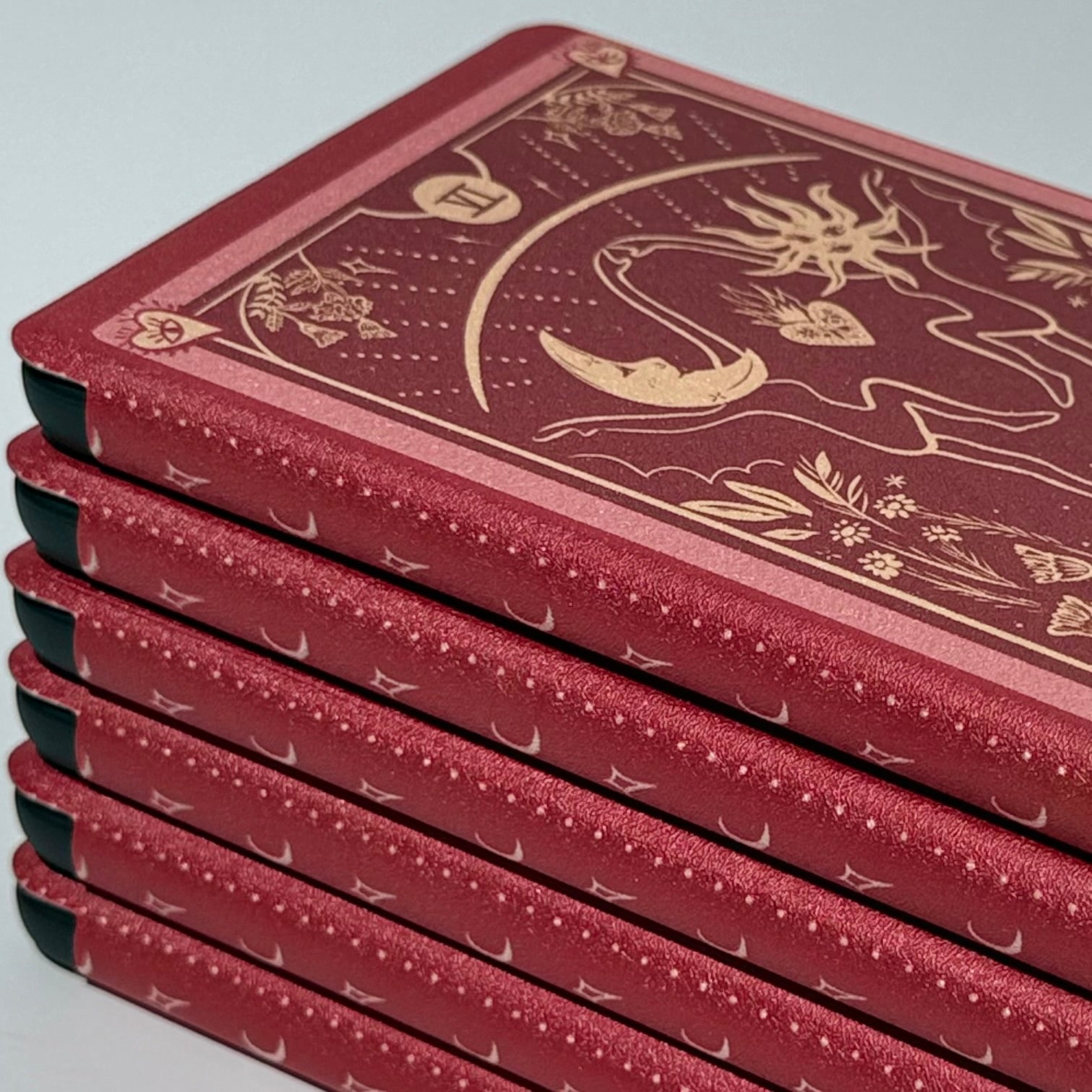 Angled stack of red tarot Kindle cases highlighting the gold moon detail and slim protective build