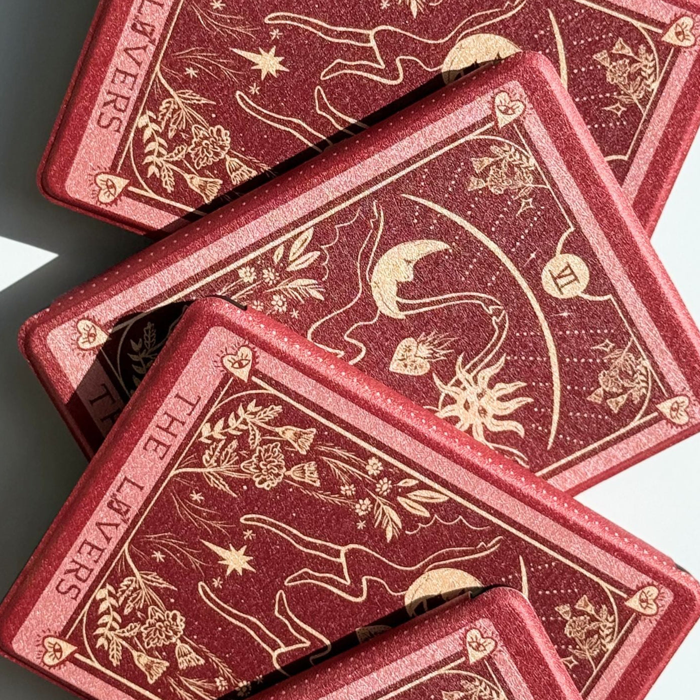 The Lovers tarot Kindle case in wine red and antique gold, two cases layered to show the celestial design
