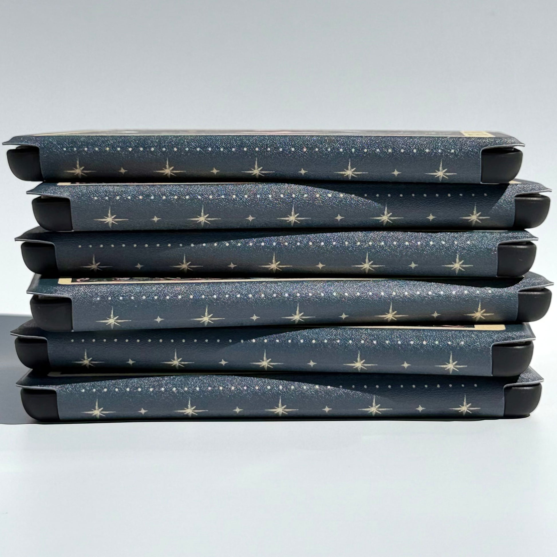 Close up of the celestial dot and star spine pattern across a stack of Kindle cases