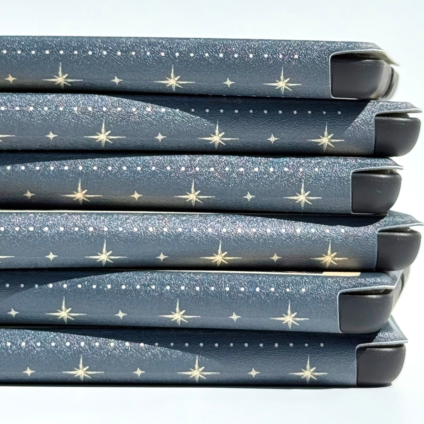 A stack of Case Society Kindle cases showing the dotted star pattern along each spine