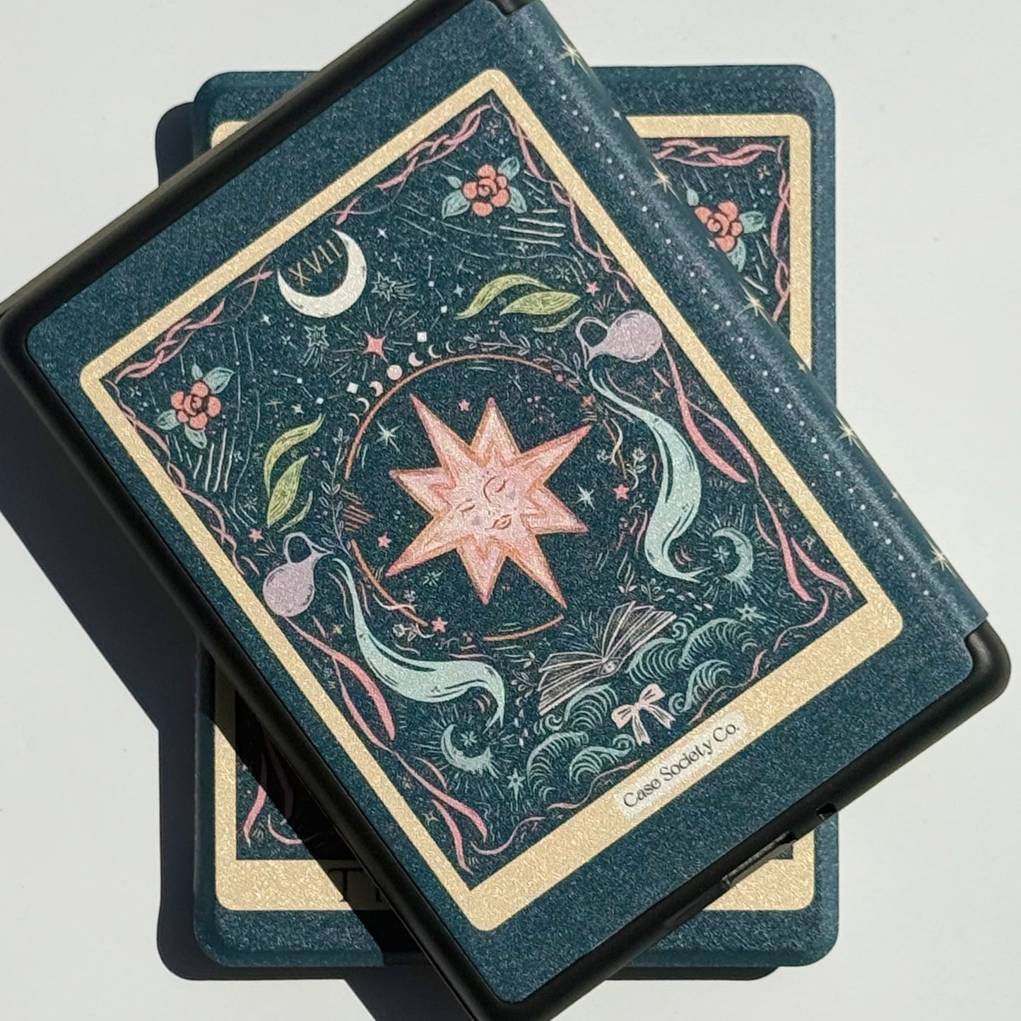 Two The Star tarot Kindle cases crossed in bright sunlight, gilt borders catching the light, Case Society Australia