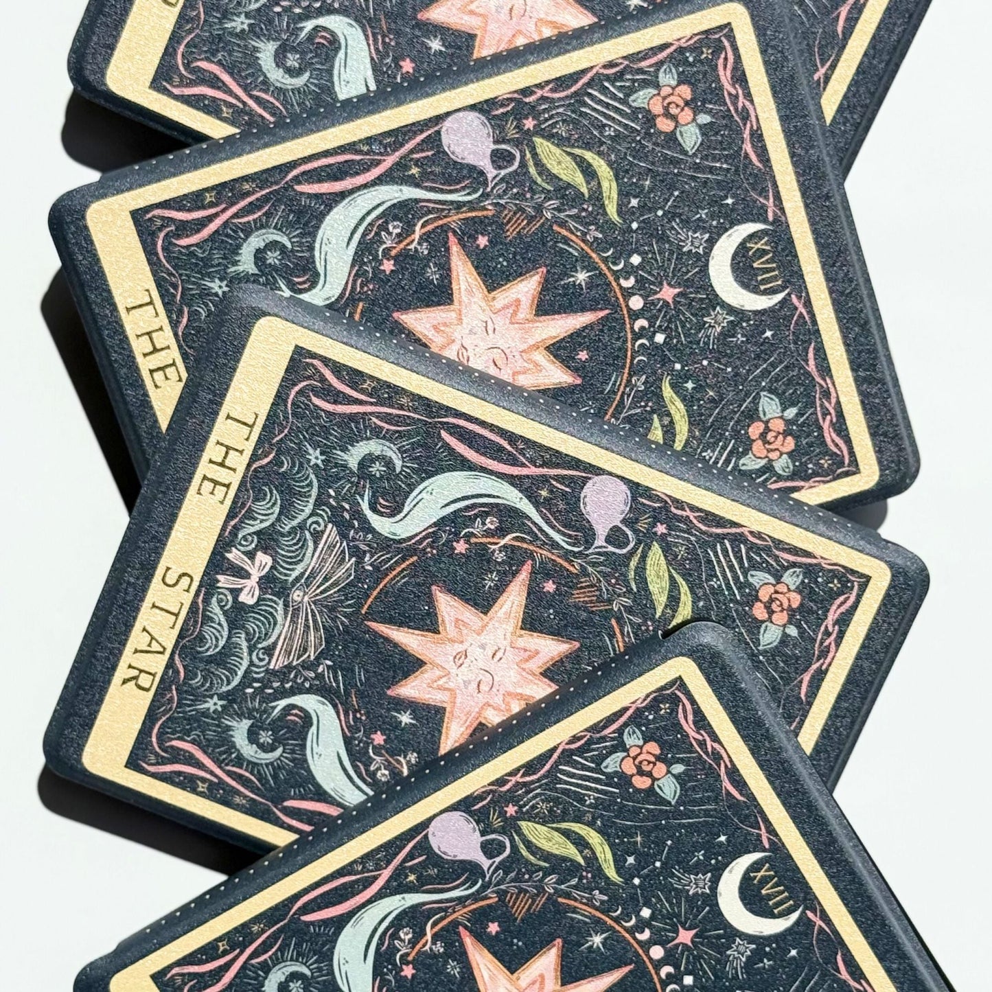 Close-up of The Star Kindle cases layered like tarot cards, peach star and crescent moon on midnight navy