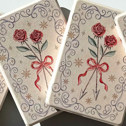 Two romantasy Kindle cases side by side, roses, red ribbon and arrows with gold stars