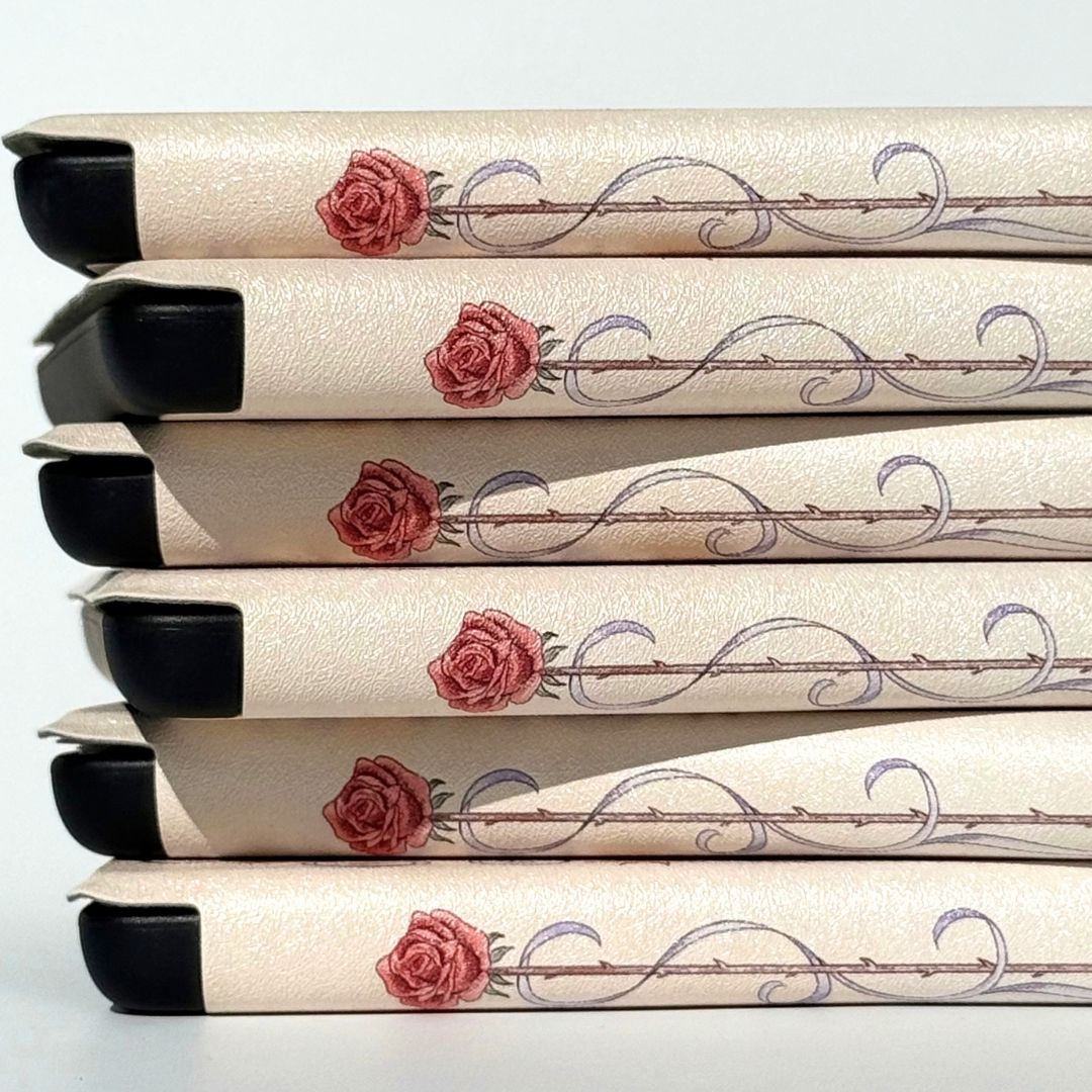 Kindle cases stacked on their sides showing the rose and thorned stem spine, Case Society Co