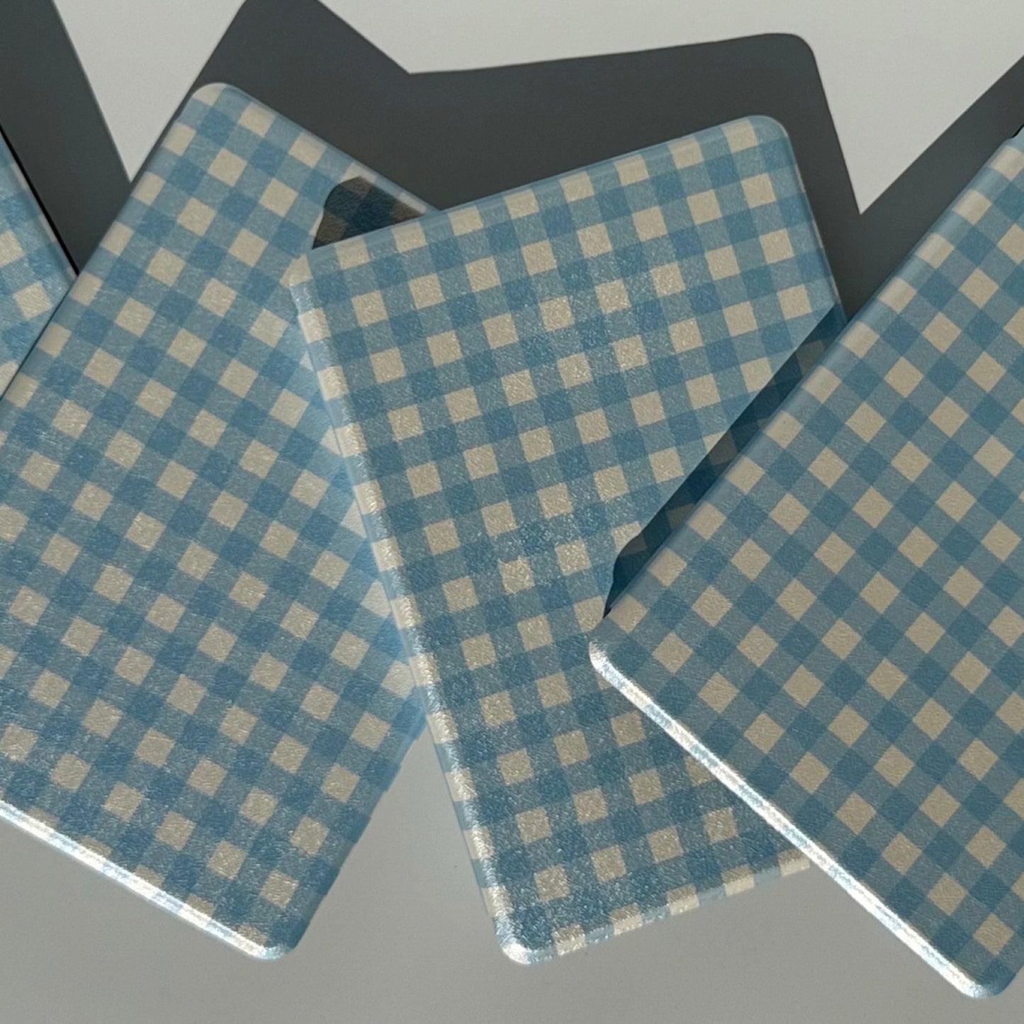 Two The Quiet Blue blue gingham Kindle cases propped at angles showing front and back