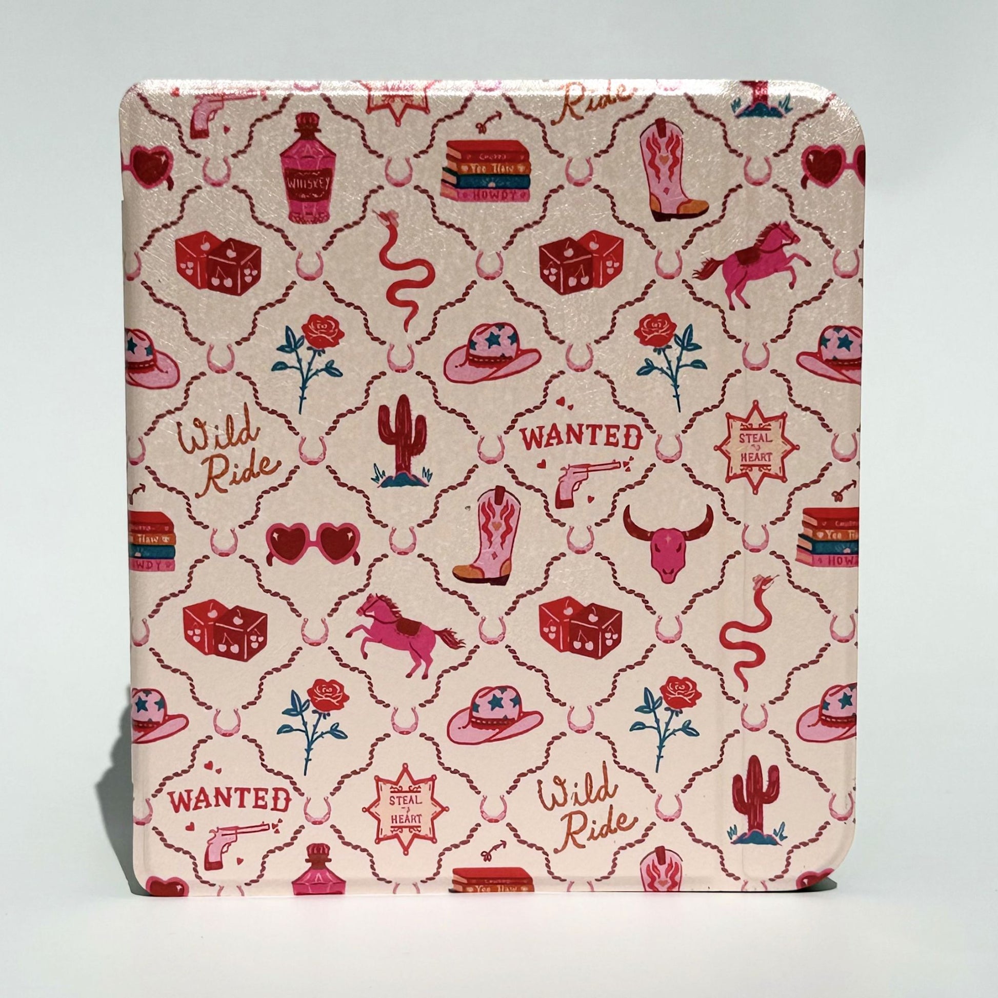 Overlapping flat lay of Wild Ride Kobo Libra cases showing pink cowboy hats, boots, horses, dice, books and roses on cream pink background